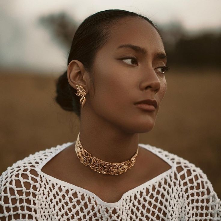 a woman in a white top is wearing a gold choker and matching necklaces