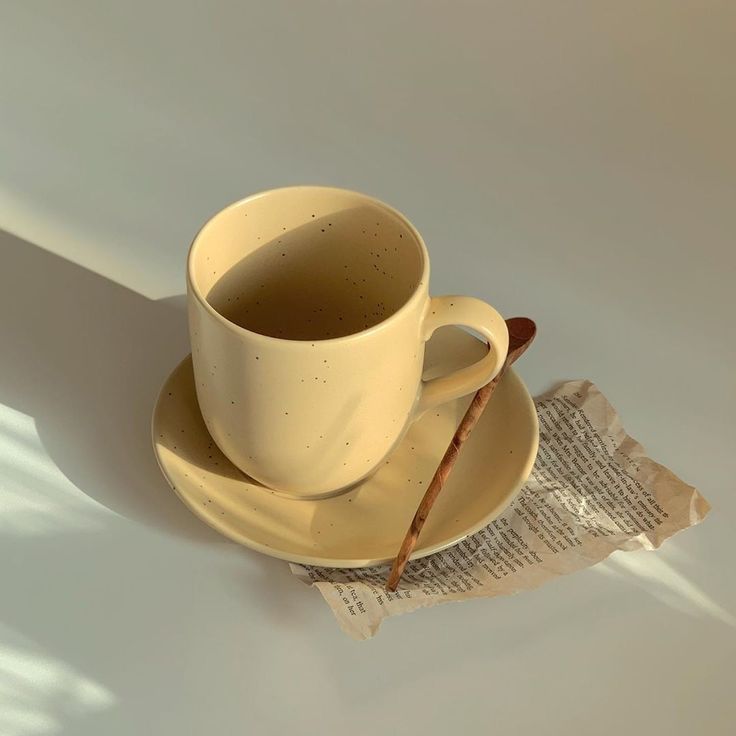 a coffee cup and saucer sitting on top of a plate next to a newspaper