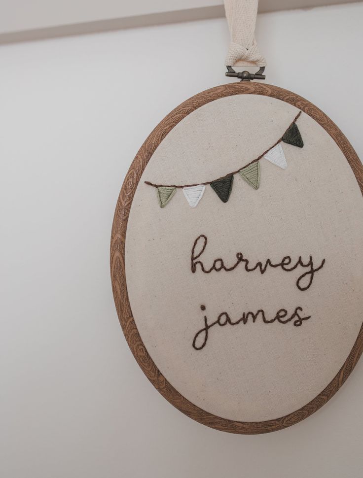 a wooden ornament hanging on the wall with a name and bunting around it