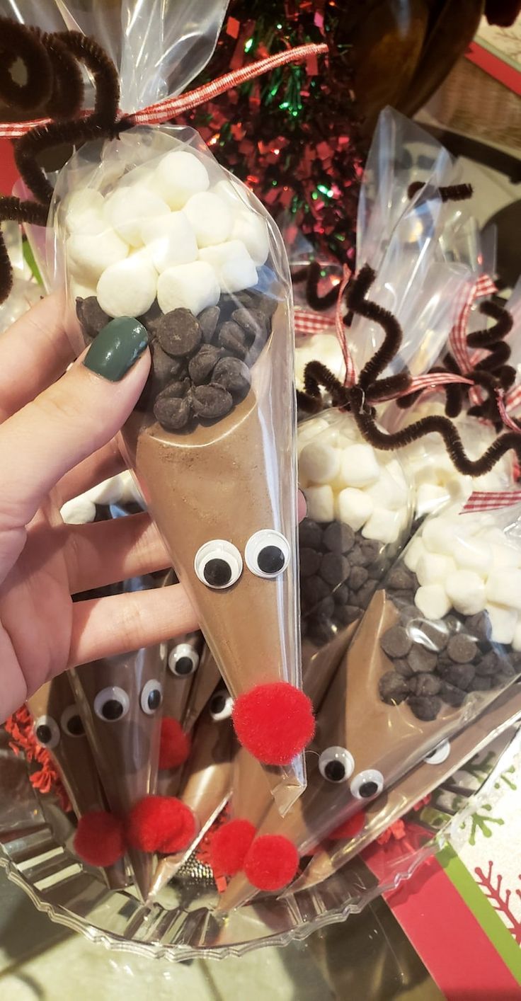 a person is holding up some candy sticks with reindeer noses on them and other decorations in the background