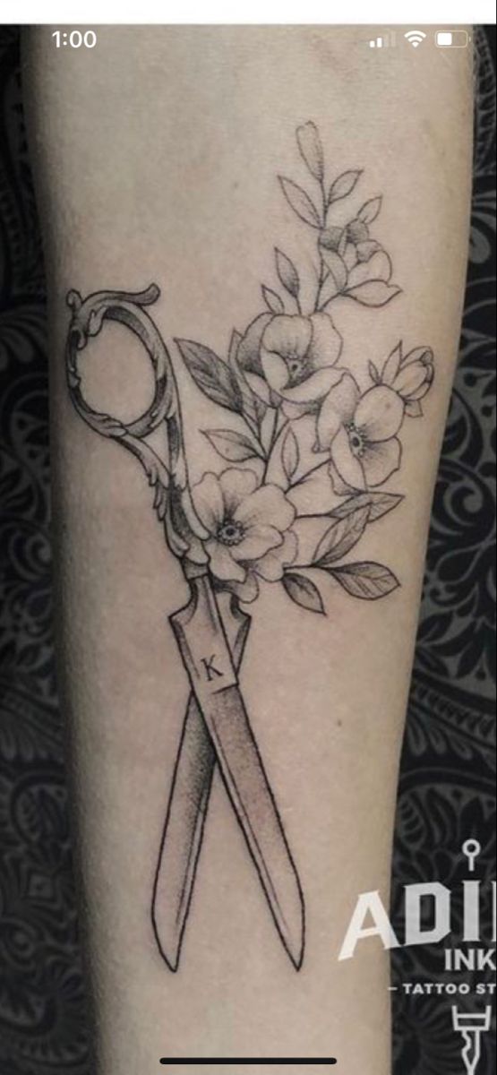 a tattoo with scissors and flowers on it