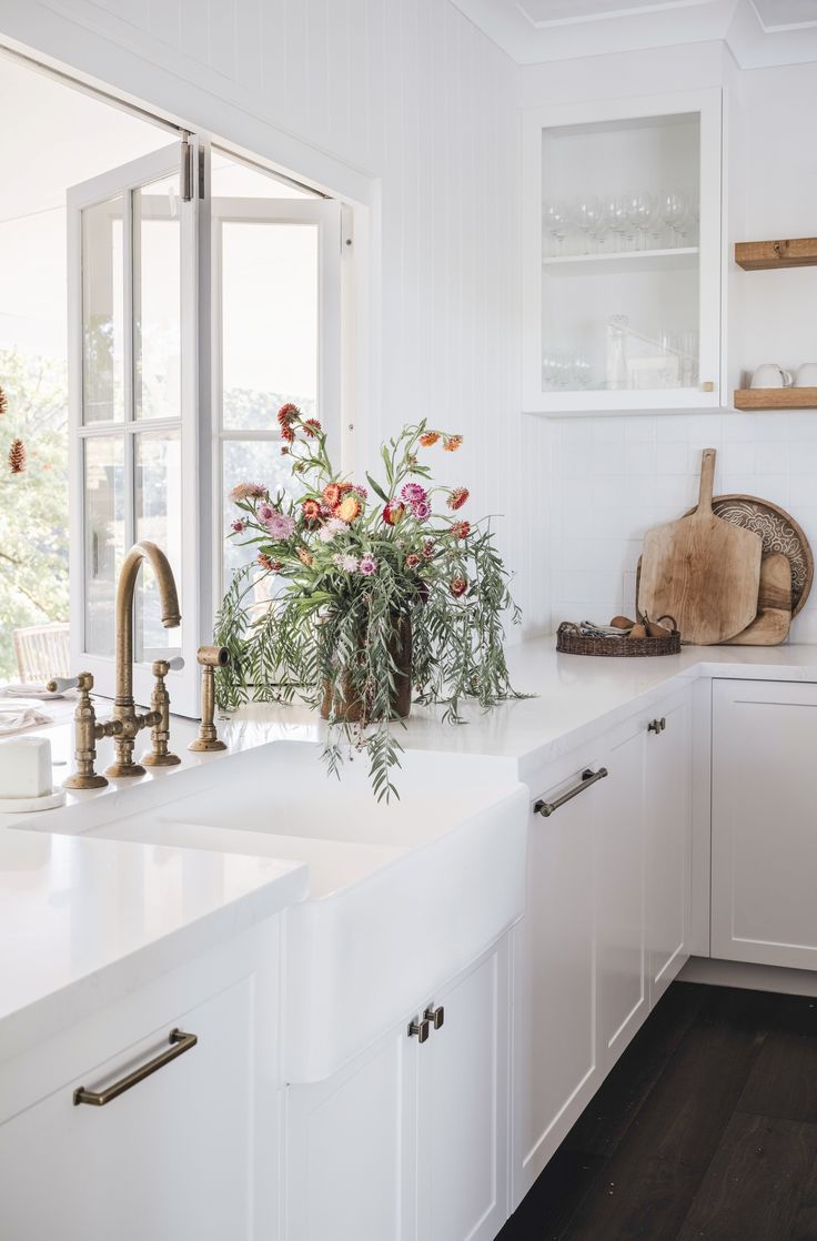 a kitchen with white cabinets and flowers on the counter