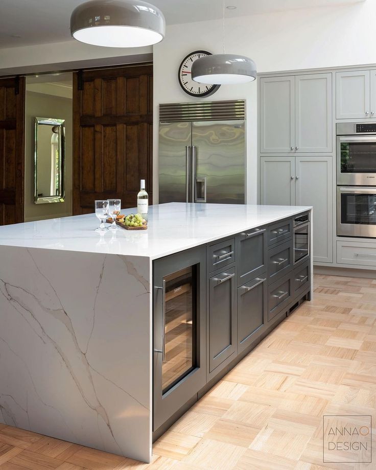 a kitchen with marble counter tops and stainless steel appliances in the center, along with wooden flooring