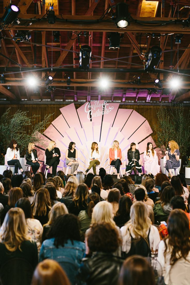 a group of women sitting on top of a stage in front of a large crowd