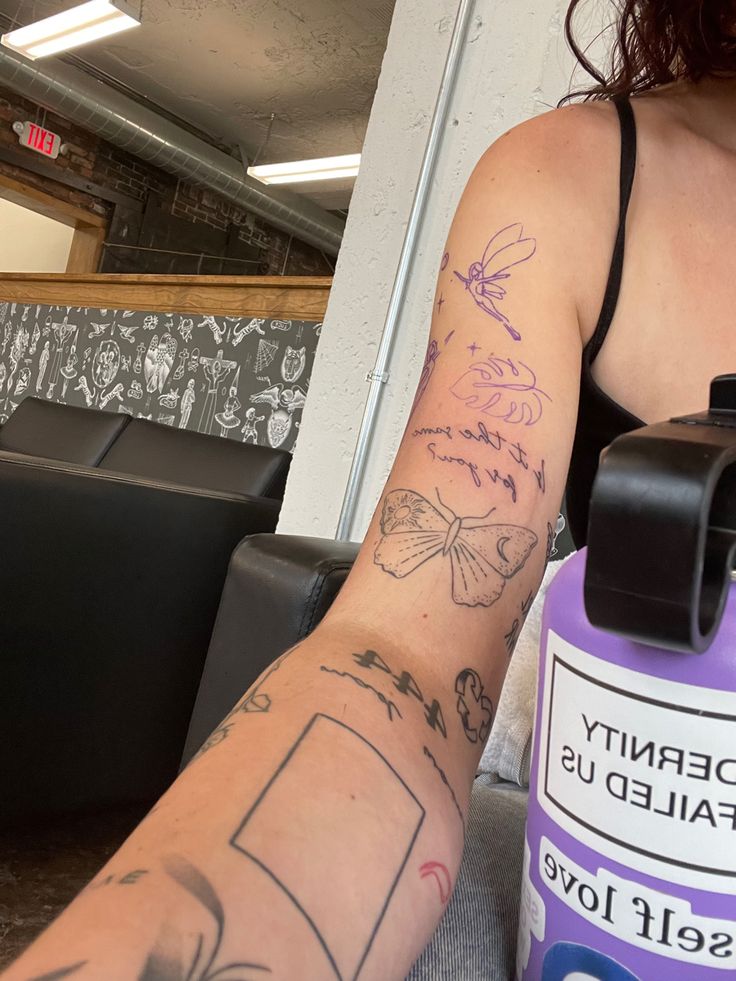 a woman with tattoos on her arm holding a purple water bottle in front of her