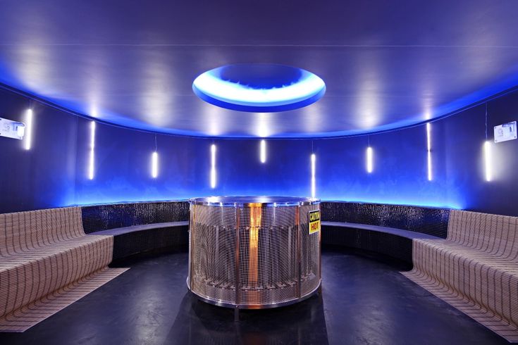 an empty room with benches and lights on the ceiling is lit up by blue lighting