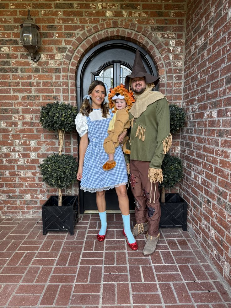 a man and woman dressed up as scarecrows standing in front of a brick building