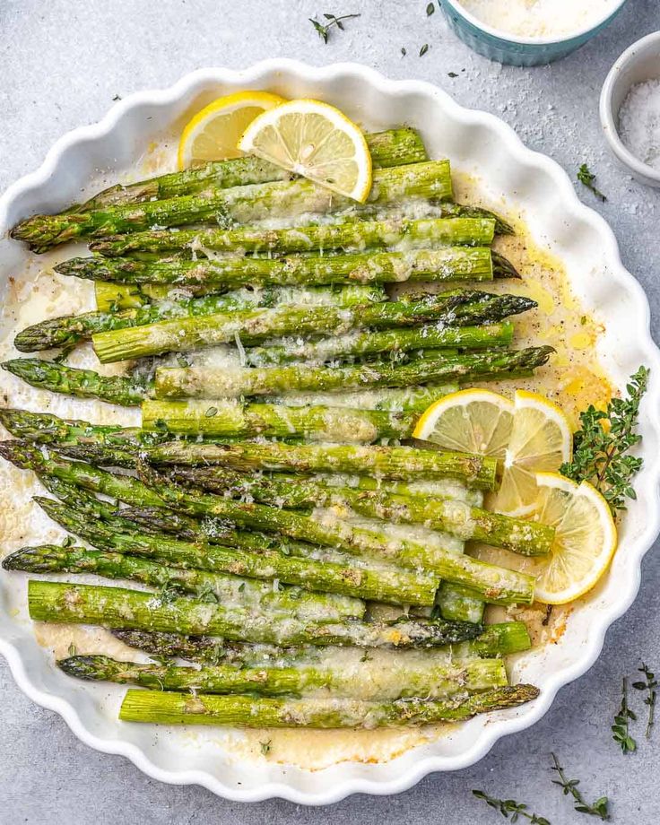 asparagus with lemon and parmesan cheese in a white dish on a table