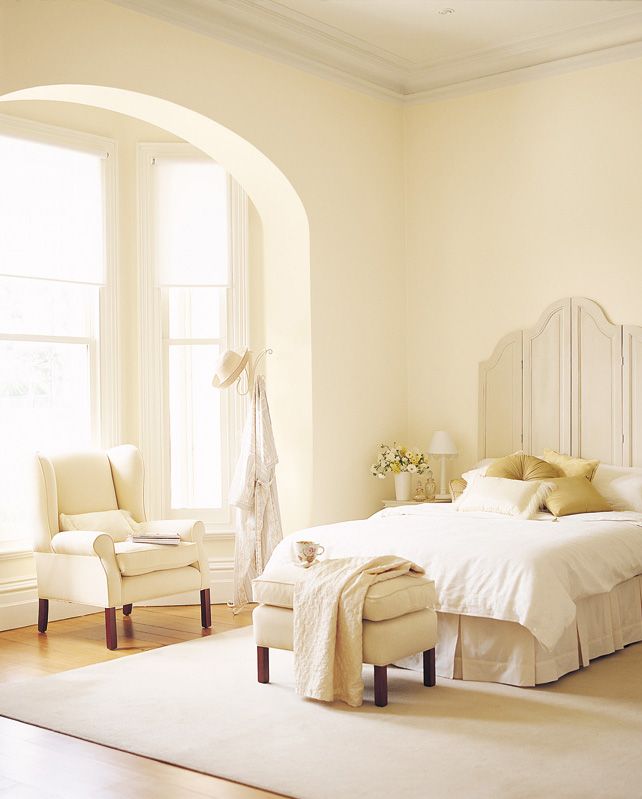 a white bed sitting in a bedroom next to two chairs