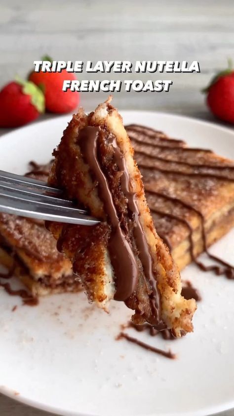 a white plate topped with french toast covered in chocolate sauce and melted strawberries next to a fork