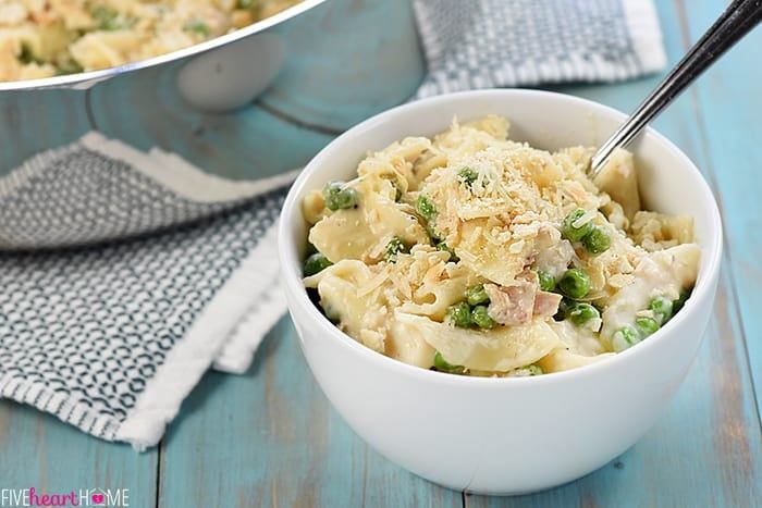 two bowls filled with macaroni and cheese sitting on top of a blue table