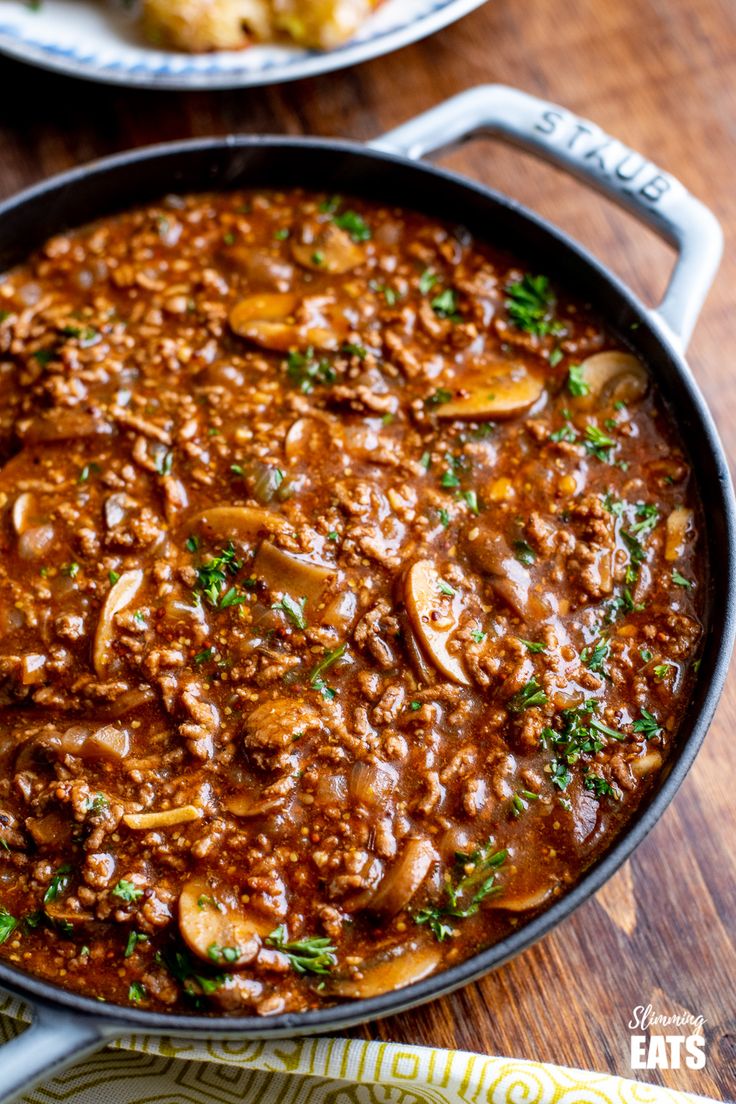 a large skillet filled with food sitting on top of a wooden table next to other dishes