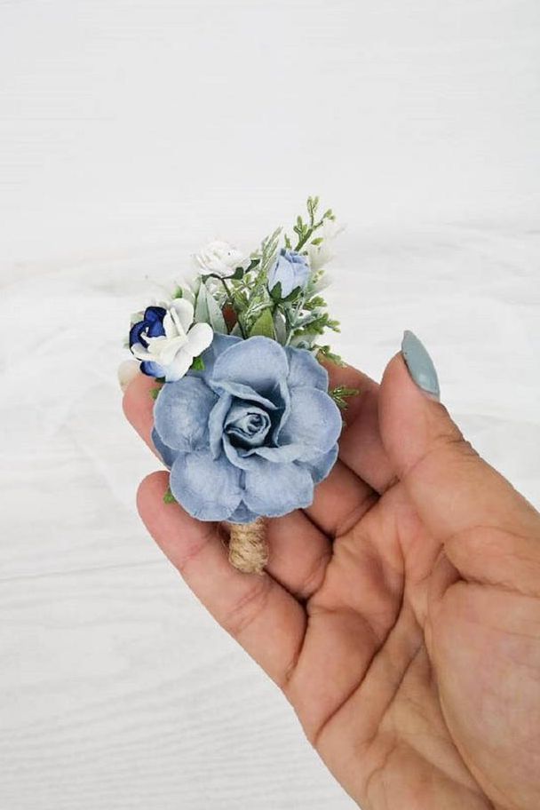 a hand holding a tiny blue flower in it's left hand on a white background