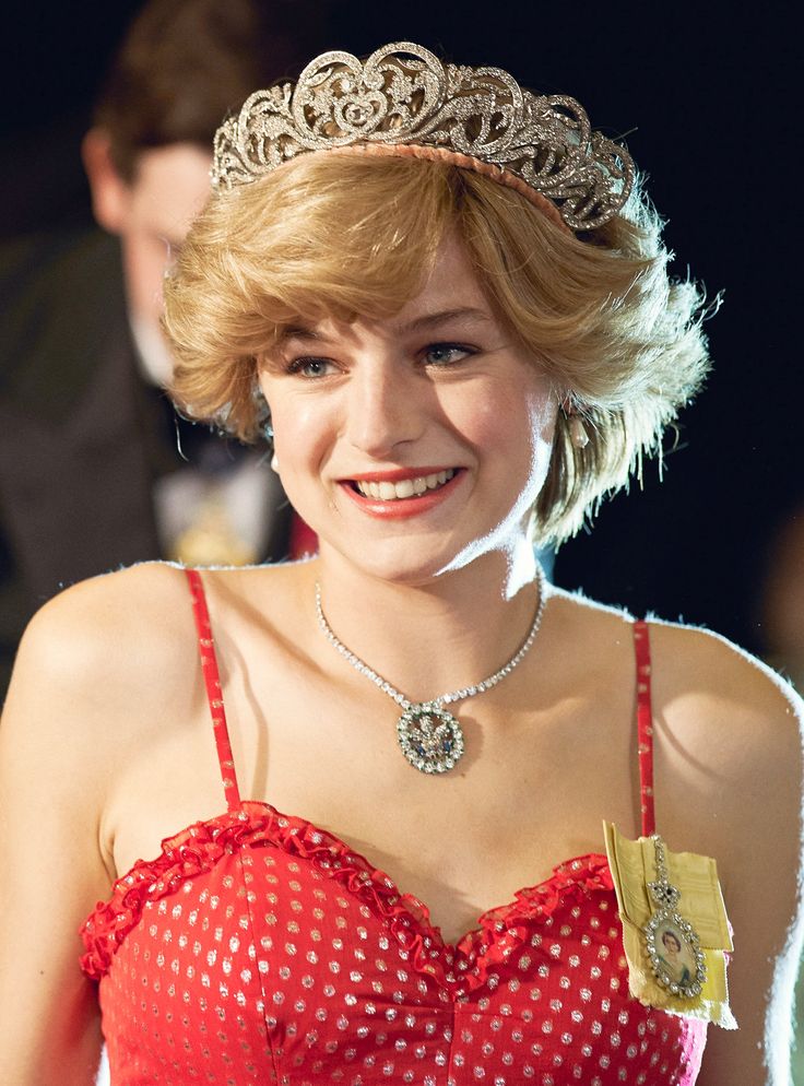 a woman wearing a tiara and smiling at the camera with other people in the background