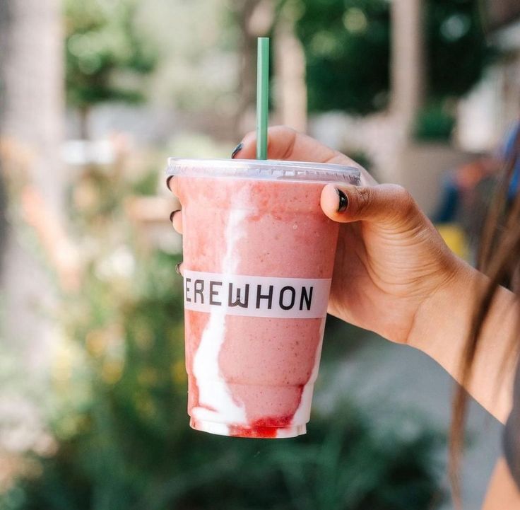 a woman holding up a pink drink with a straw in it's cup and the words freewhon written on it