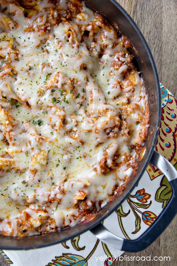 a casserole dish with cheese and meat in it sitting on a colorful plate