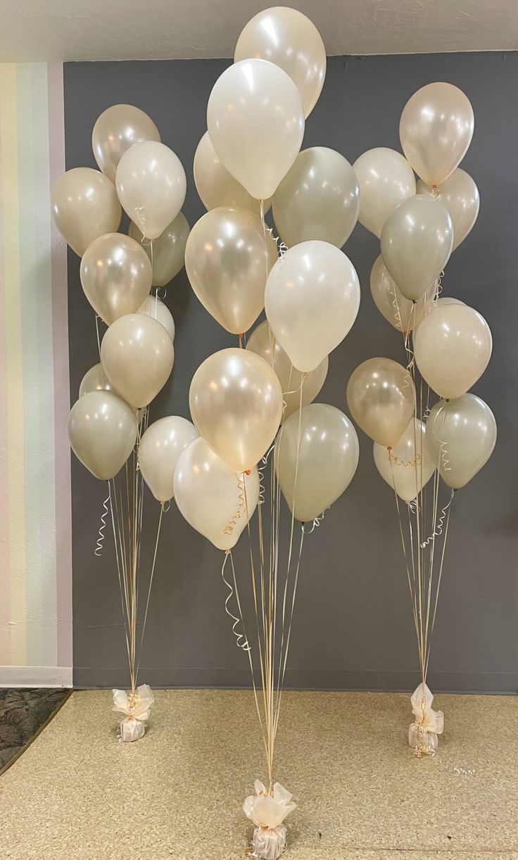 a bunch of balloons that are sitting on the ground in front of a wall,