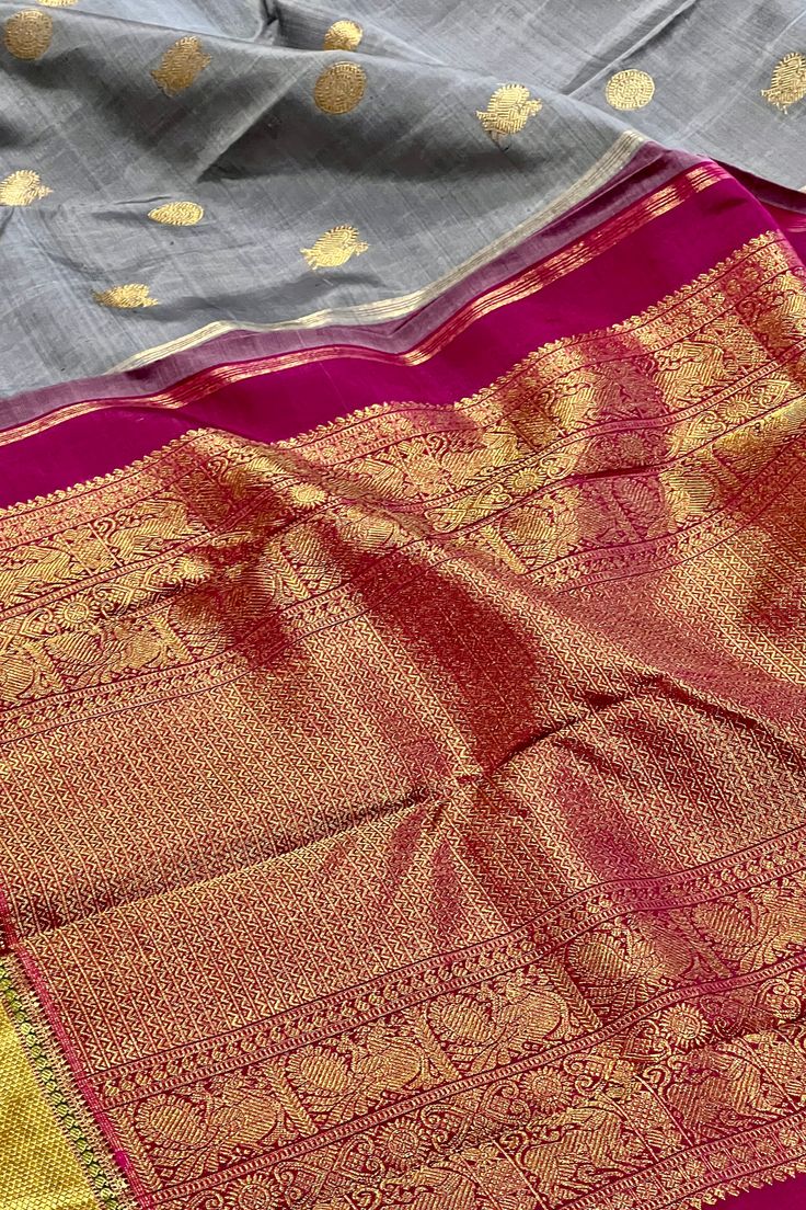 This stunning kanjivaram saree in english grey is handwoven. The bavanji borders have geometrical patterns in magenta pink in gold zari! This exquisite saree is adorned with chakram and peacock motifs in gold zari while the grand pallu with traditional annam motifs in gold zari. Truly a masterpiece! Approximate Length 6.25 - 6.50 mtrs (inclusive of blouse length) Approximate Height - 46 - 52” Saree comes with fall, picot and tassels done when applicable . Blouse piece is cut. Approximate weight Gray Traditional Wear For Festive Occasions, Festive Gray Traditional Wear, Gray Festive Traditional Wear, Festive Saree With Border For Rituals, Traditional Gray Wear With Pallu, Gray Traditional Wear With Pallu, Gray Traditional Wear For Diwali, Festive Gray Traditional Wear With Pallu, Traditional Gray Saree With Pallu