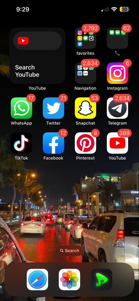 an iphone screen with several different icons on the screens and in the background, cars driving down a city street at night