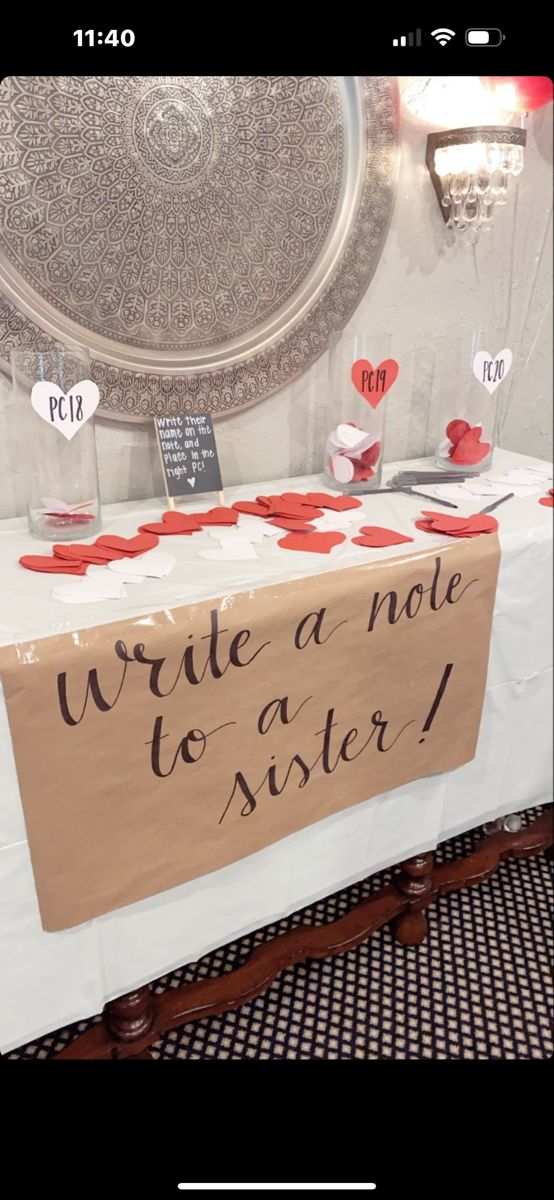 a table with a sign that says write a note to sister on it and red hearts