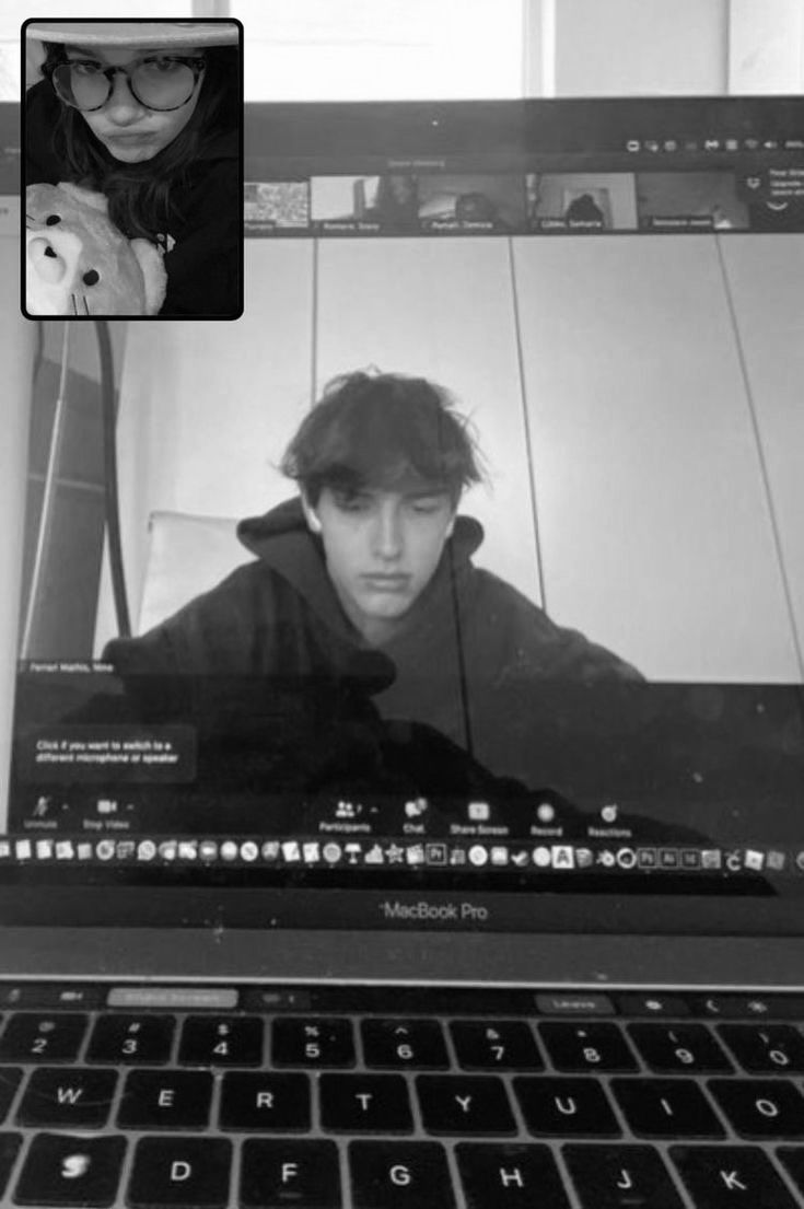 a black and white photo of a person on a laptop computer with the image of a man's face