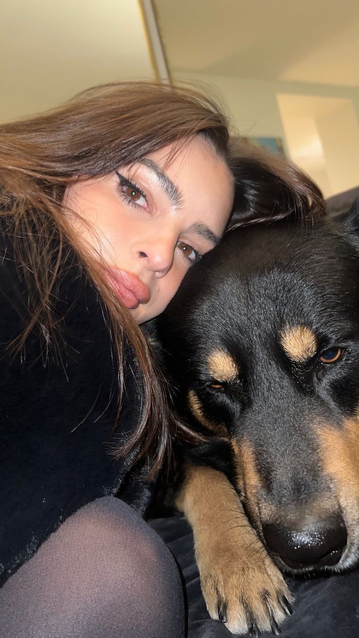 a woman laying on top of a couch next to a black and brown dog in her lap