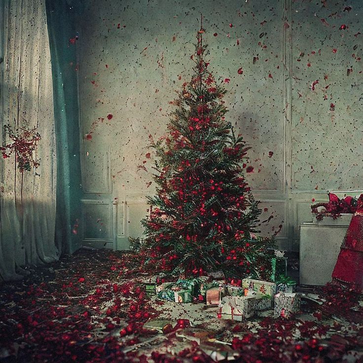 a christmas tree surrounded by presents and confetti on the floor in an old room