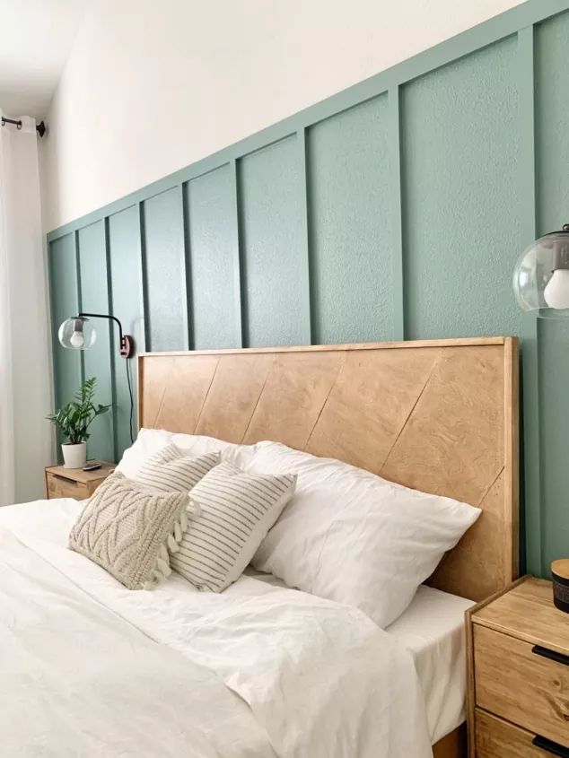 a bed with white sheets and pillows next to a green painted wall in a bedroom