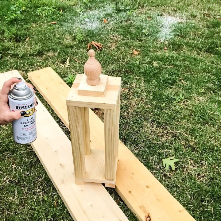 someone is painting the outside of a wooden lantern on some wood planks and it's being used to make a candle holder