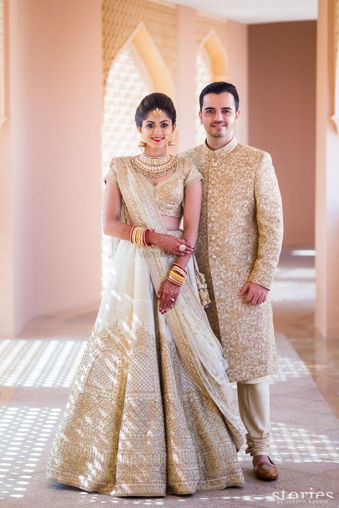 a man and woman standing next to each other in wedding outfits, posing for the camera