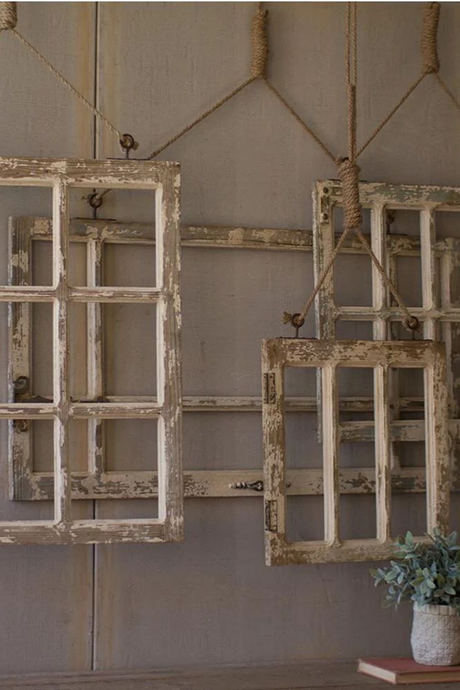 two old window frames hanging on the wall next to a vase with flowers in it