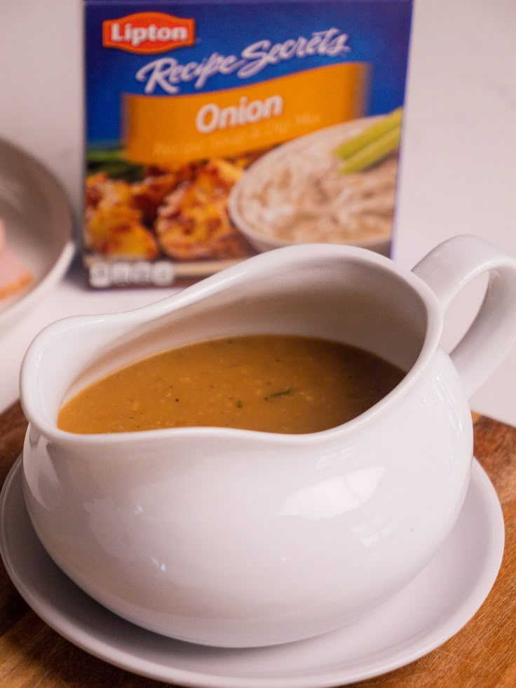 a bowl of soup on a plate next to a carton of soup