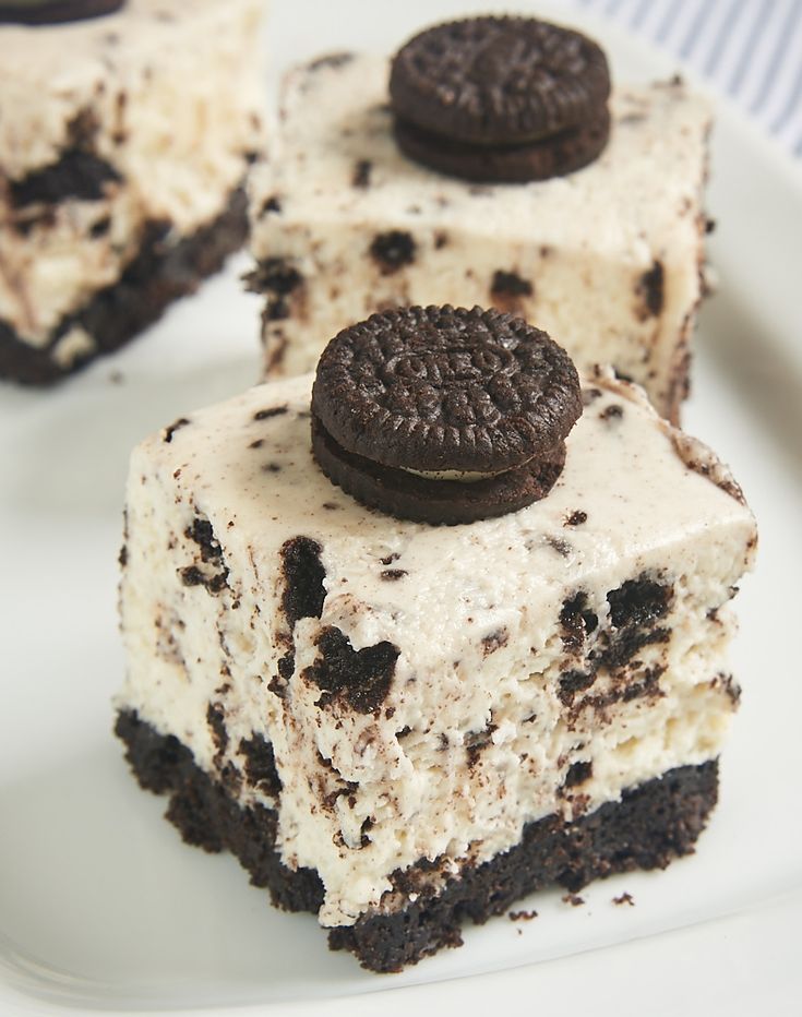 three oreo cookies and cream cheesecake squares on a white plate with a fork