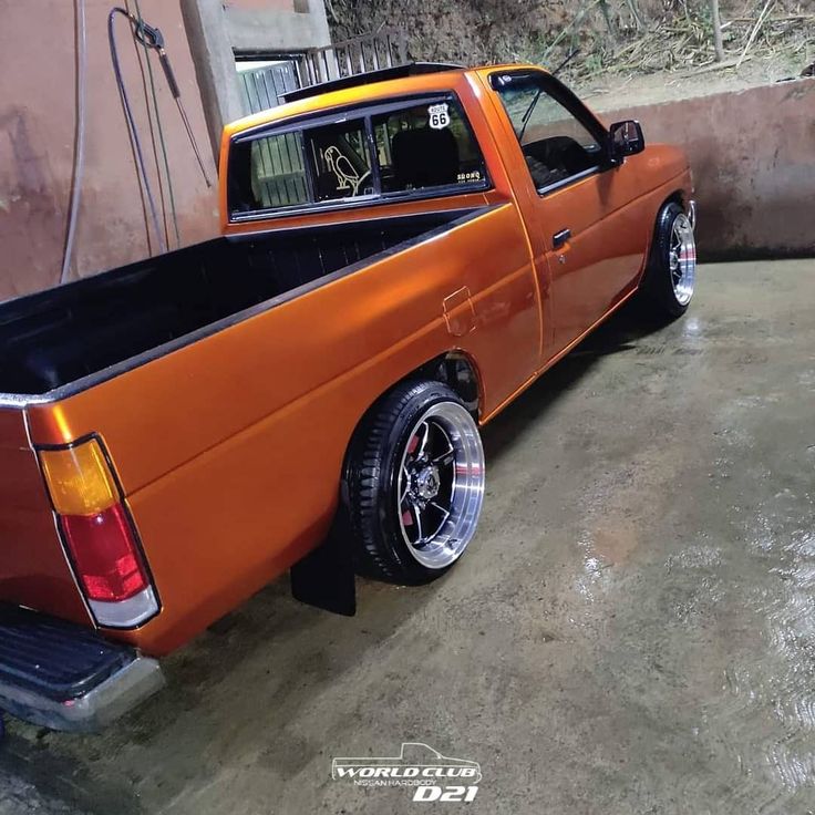 an orange pick up truck parked in a garage