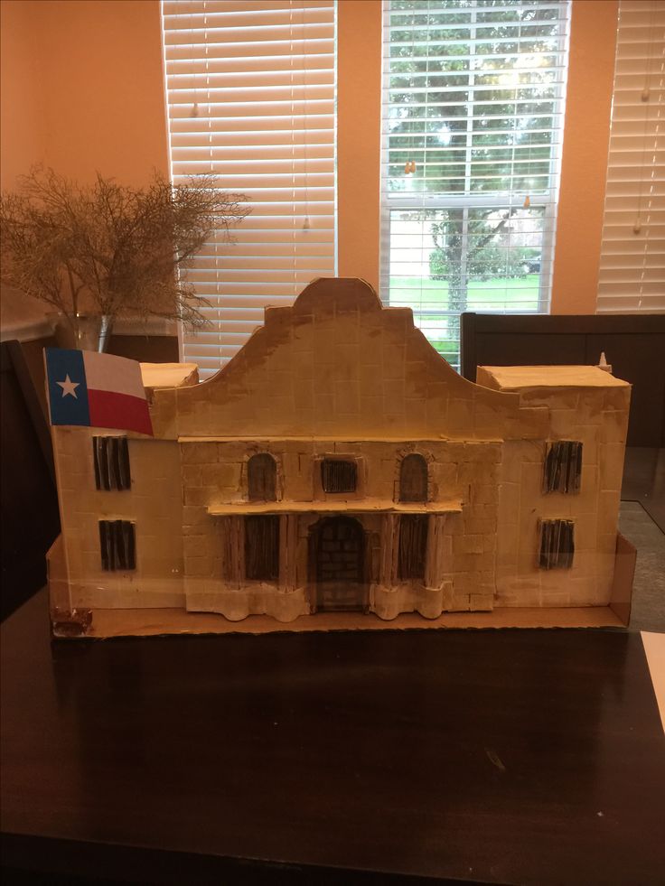 a model of a house on a table in front of a window with shutters