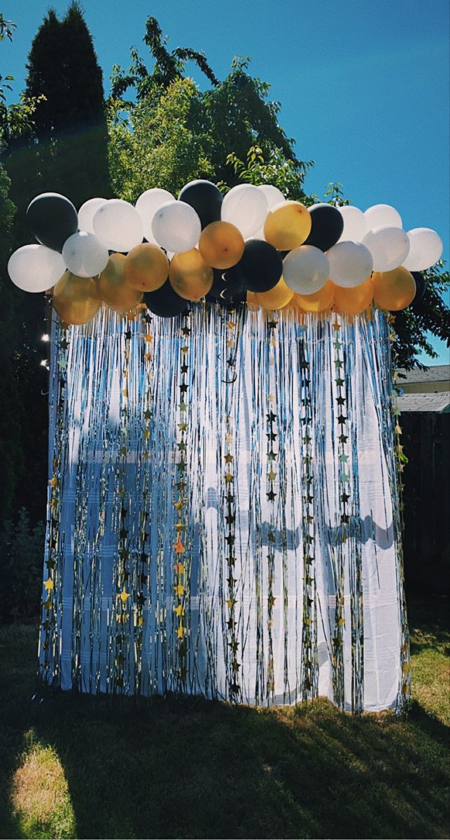 a bunch of balloons hanging from the side of a curtain in front of a house