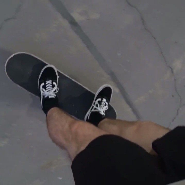 a person wearing black and white shoes standing next to a skateboard