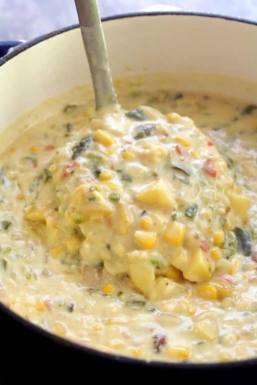 a spoon is in a pot filled with corn and broccoli cheese soup, ready to be eaten