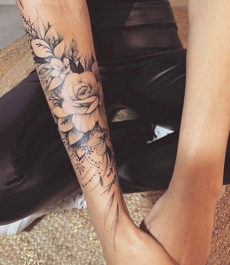 two people sitting on the ground with their legs crossed and one has a flower tattoo on it