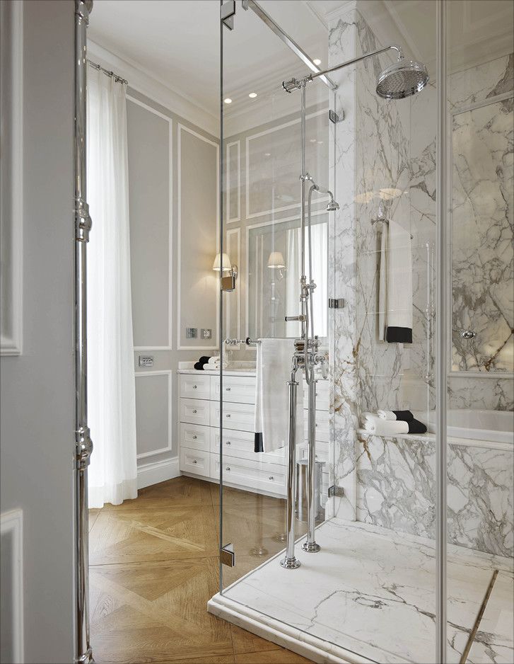 an elegant bathroom with marble walls and flooring is pictured in this image, there are lights on either side of the shower