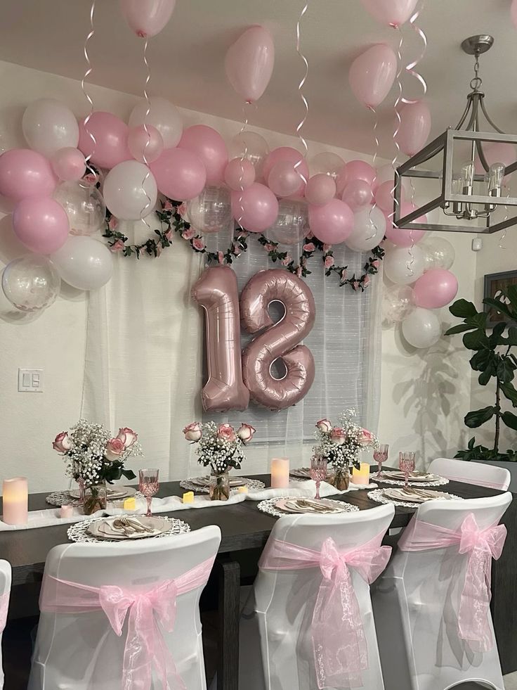 the table is set with pink and white balloons