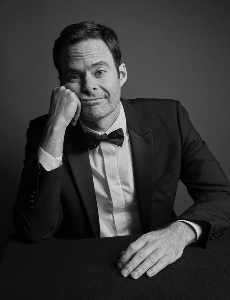 a black and white photo of a man in a tuxedo sitting at a table