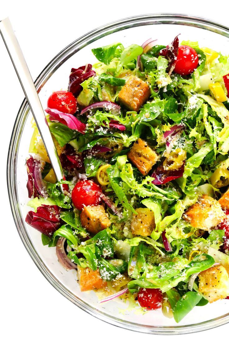 a salad with lettuce, tomatoes and croutons in a glass bowl