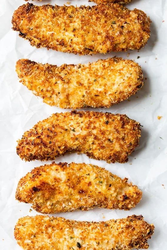 four pieces of fried chicken sitting on top of white paper