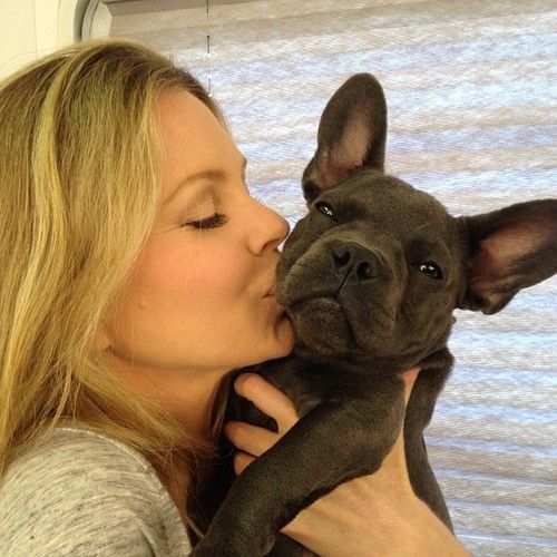 a woman kissing a small dog with her nose close to it's face,