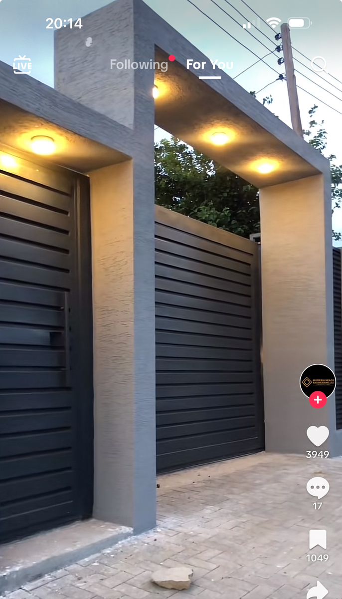 an image of a house with two garage doors and some lights on the side of it