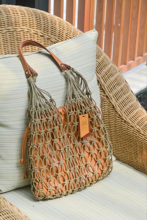 an orange purse sitting on top of a white pillow next to a wicker chair