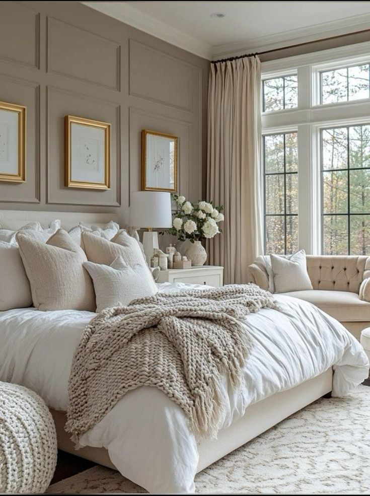 a large white bed sitting in a bedroom next to a window filled with lots of windows