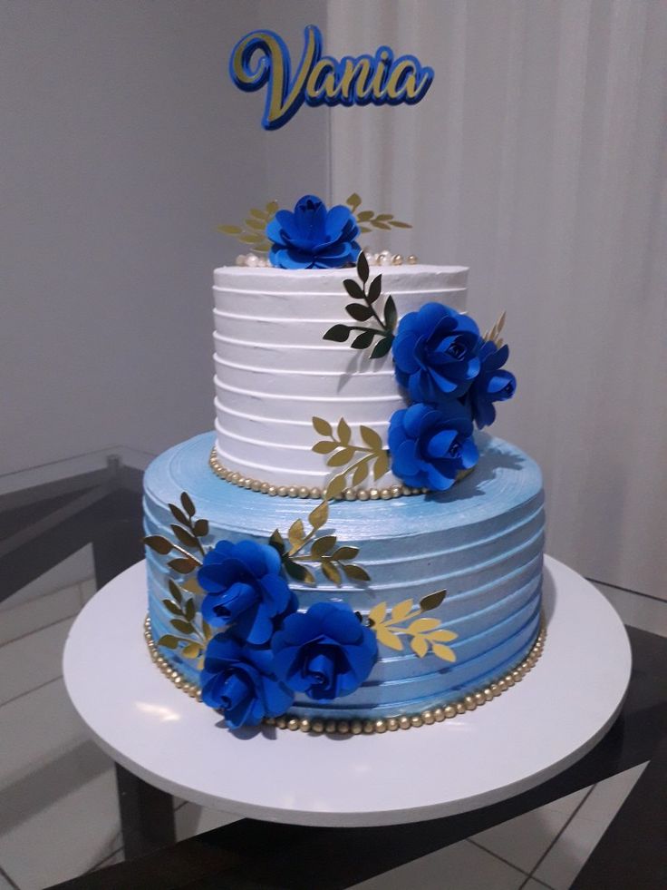 a three tiered cake with blue flowers on it and the name vanilla written on top