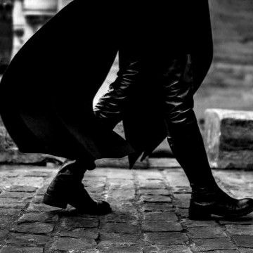 a man dressed in all black walking down the street